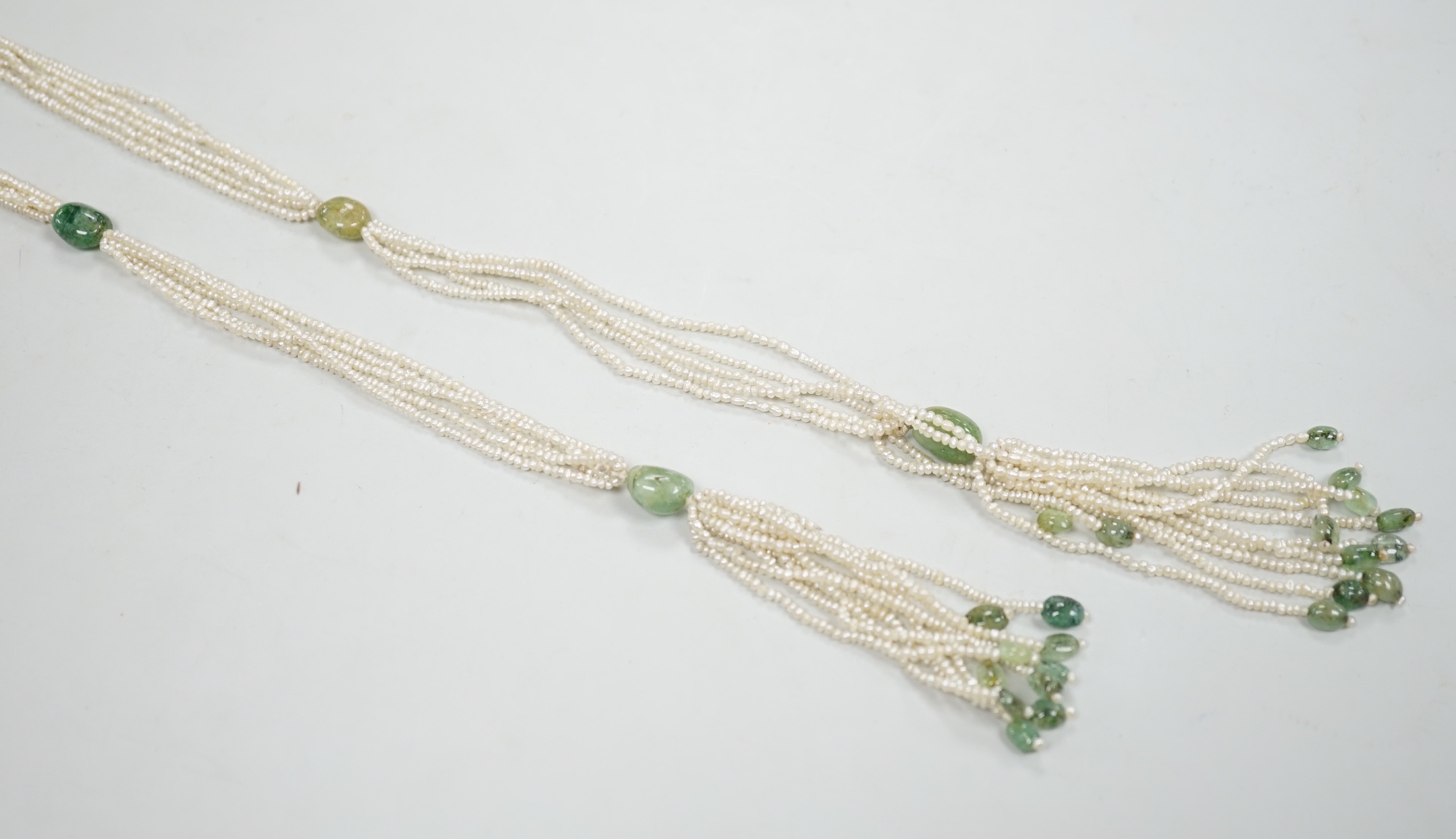 A 19th century Indian multi strand seed pearl and emerald? set long necklace, with gem set tassel drops, 176cm.
